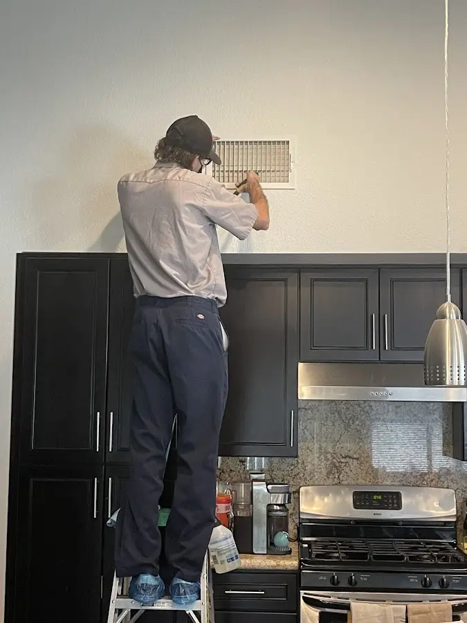 Technician inspecting an air vent during HVAC service in Atascadero